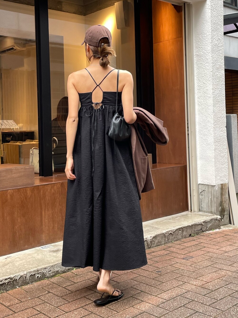 ブラック系のワンピース、ブラック系のサンダル、ブラウン系のキャップを着用したレディースの夏コーディネートの2枚目の写真