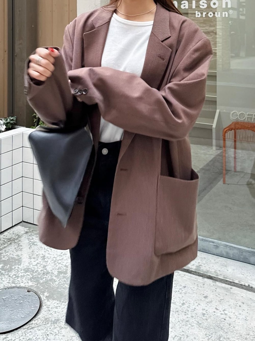 ホワイト系のTシャツ/カットソー、ブラウン系のテーラードジャケット、ブラック系のハンドバッグを着用したレディースの秋コーディネートの3枚目の写真