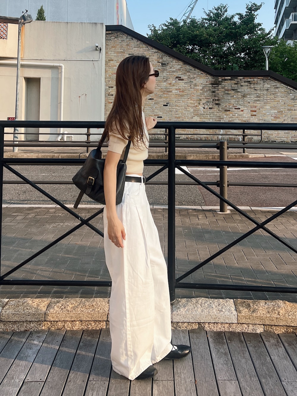 ベージュ系のニット/セーター、ホワイト系のデニムパンツ、ブラック系のスニーカーを着用したレディースの秋コーディネートの2枚目の写真