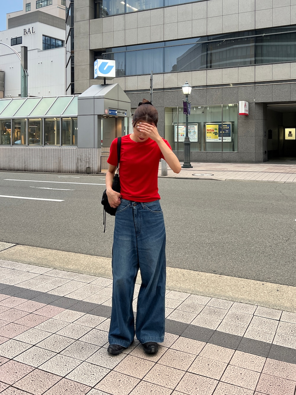 レッド系のTシャツ/カットソー、ブルー系のデニムパンツ、ブラック系のショルダーバッグを着用したレディースの夏コーディネートの4枚目の写真