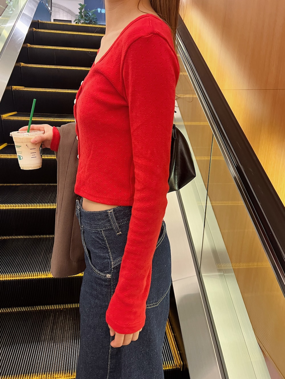 レッド系のカーディガン/ボレロ、ブルー系のデニムパンツ、ブラウン系のモカシン/デッキシューズを着用したレディースの春コーディネートの3枚目の写真