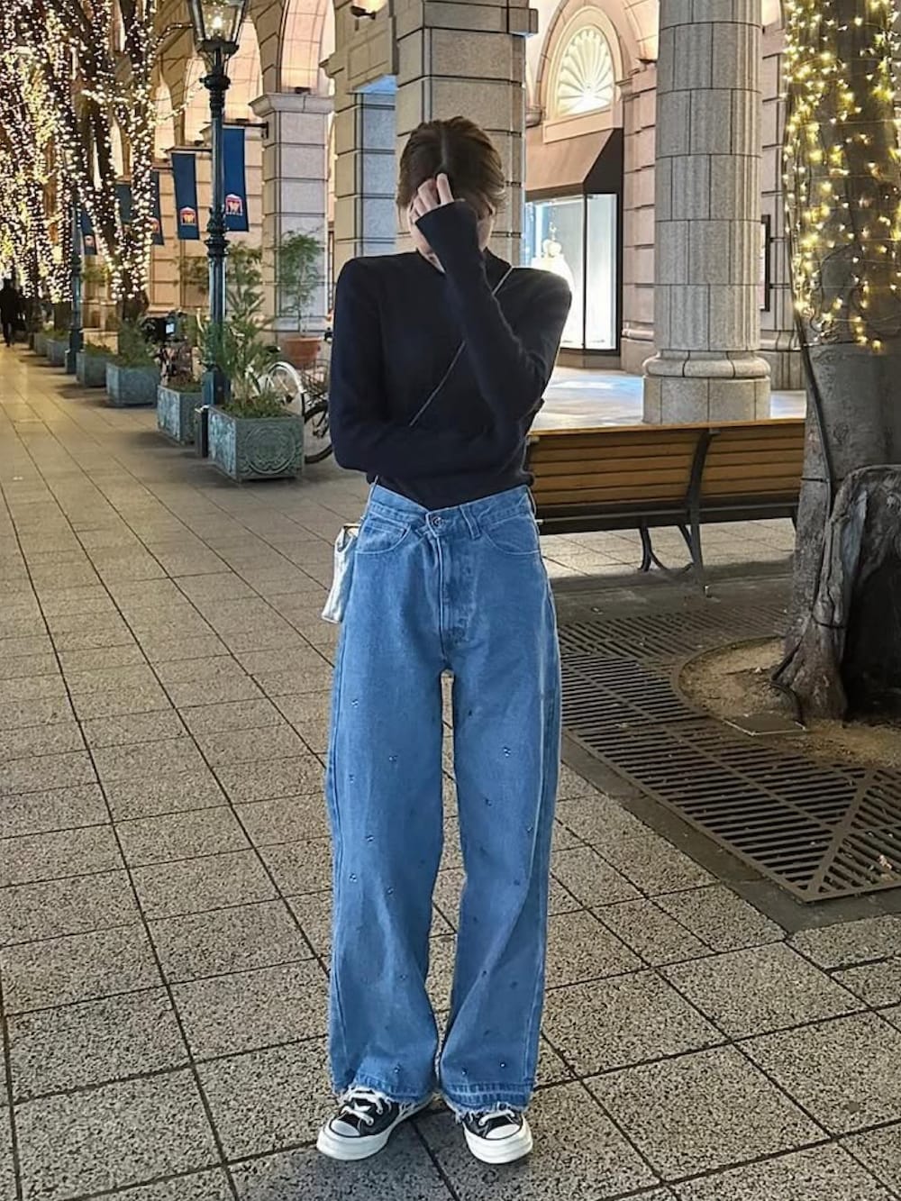 ブラック系のムートンコート、シルバー系のショルダーバッグ、ブルー系のデニムパンツを着用したレディースの冬コーディネートの2枚目の写真