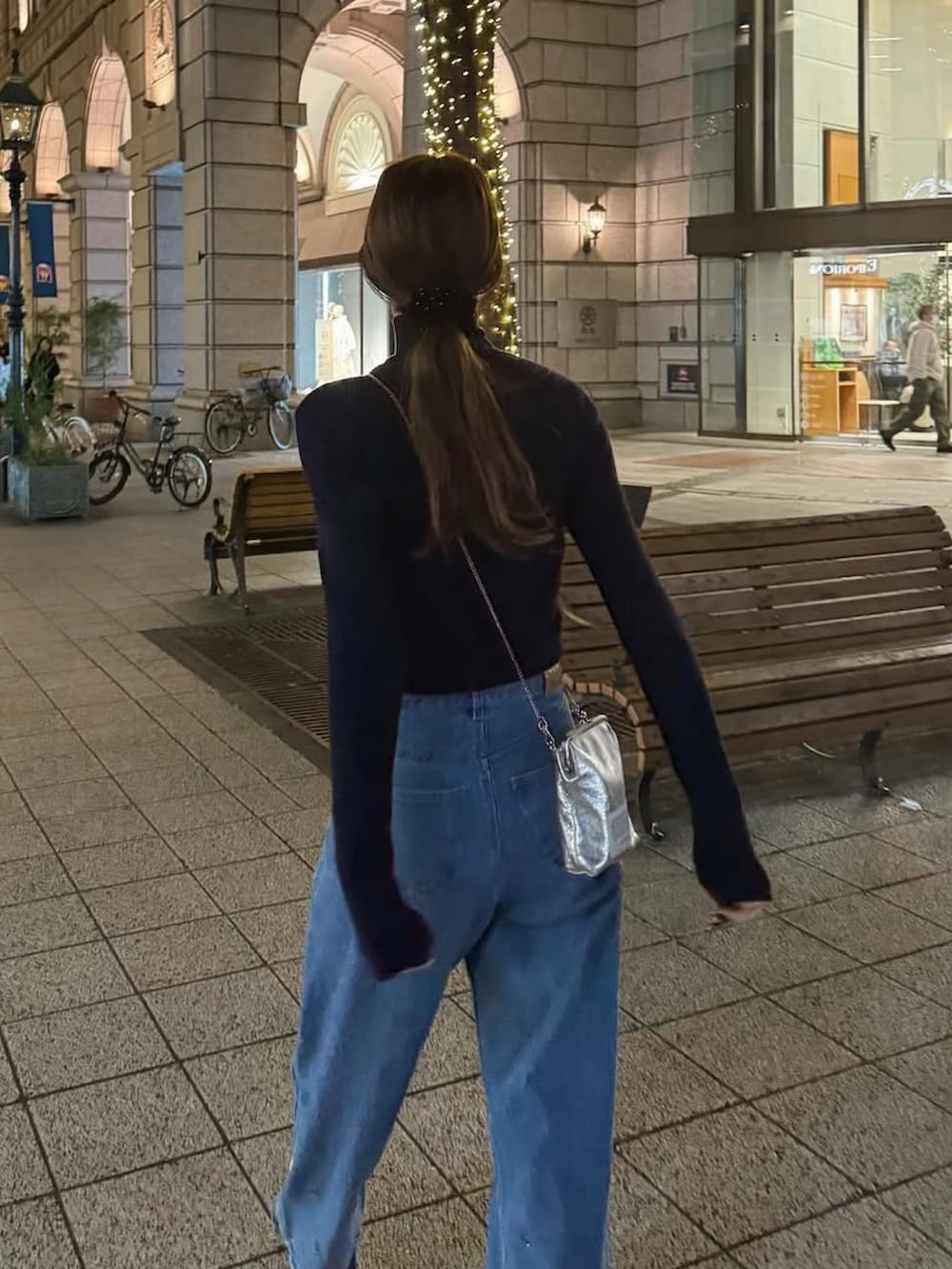 ブラック系のムートンコート、シルバー系のショルダーバッグ、ブルー系のデニムパンツを着用したレディースの冬コーディネートの3枚目の写真