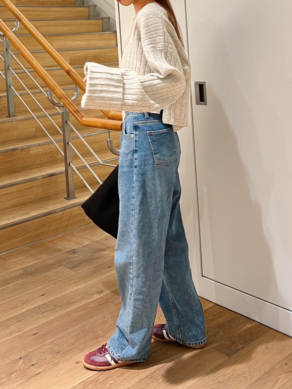 ホワイト系のニット/セーター、ブルー系のデニムパンツ、レッド系のスニーカーを着用したレディースの秋コーディネートの2枚目の写真