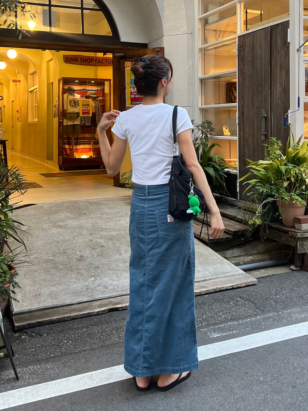 ブラック系のショルダーバッグ、ブラック系のサンダル、ブルー系のスカートを着用したレディースの夏コーディネートの2枚目の写真