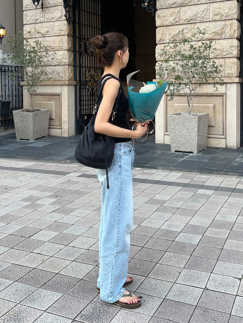 ブラック系のタンクトップ、ブルー系のデニムパンツ、グリーン系のサンダルを着用したレディースの夏コーディネートの2枚目の写真