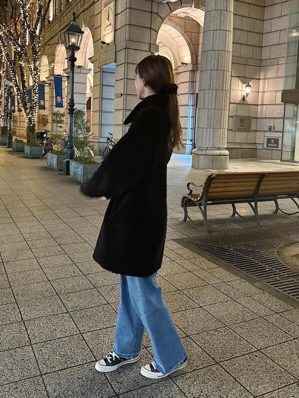 ブラック系のムートンコート、シルバー系のショルダーバッグ、ブルー系のデニムパンツを着用したレディースの冬コーディネートの4枚目の写真