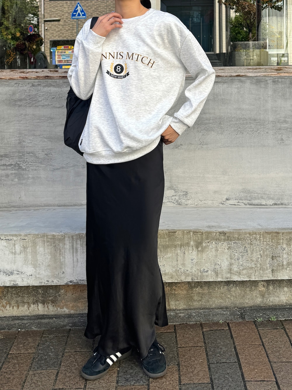 グレー系のスウェット、ブラック系のバックパック/リュック、ブラック系のスカートを着用したレディースの秋コーディネートの2枚目の写真