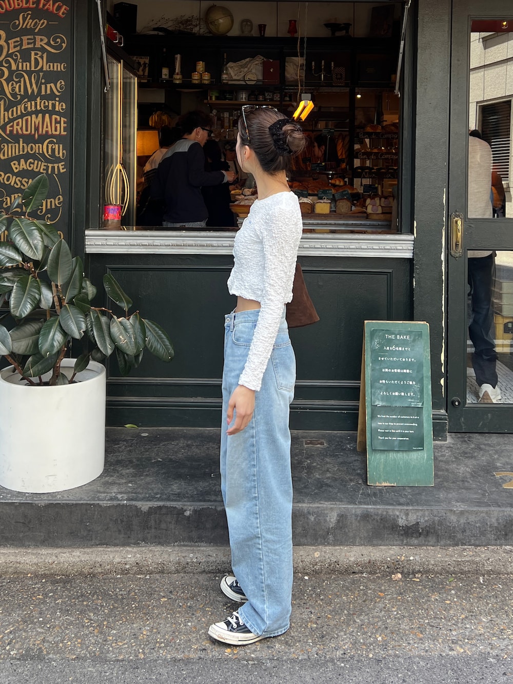 ホワイト系のカーディガン/ボレロ、ブルー系のデニムパンツ、ブラウン系のハンドバッグを着用したレディースの春コーディネートの2枚目の写真