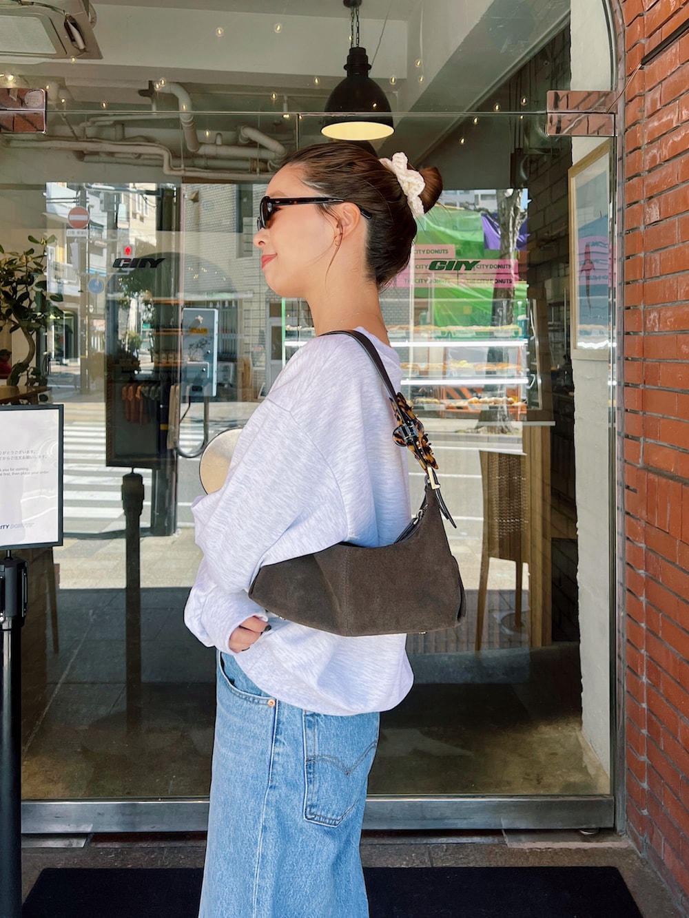 グレー系のTシャツ/カットソー、ブルー系のデニムパンツ、ブラウン系のモカシン/デッキシューズを着用したレディースの春コーディネートの2枚目の写真