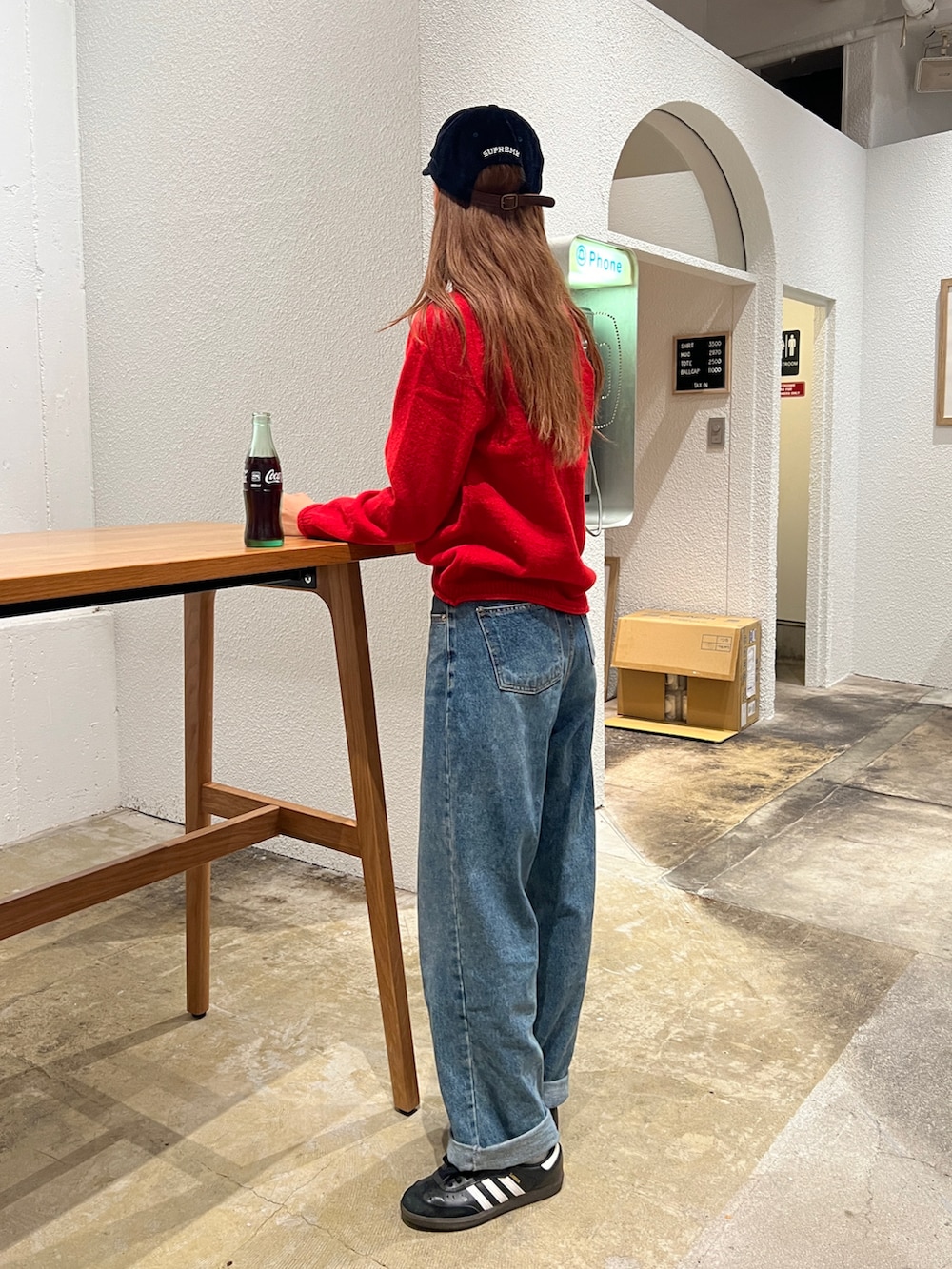 レッド系のニット/セーター、ブルー系のデニムパンツ、シルバー系のショルダーバッグを着用したレディースの秋コーディネートの4枚目の写真