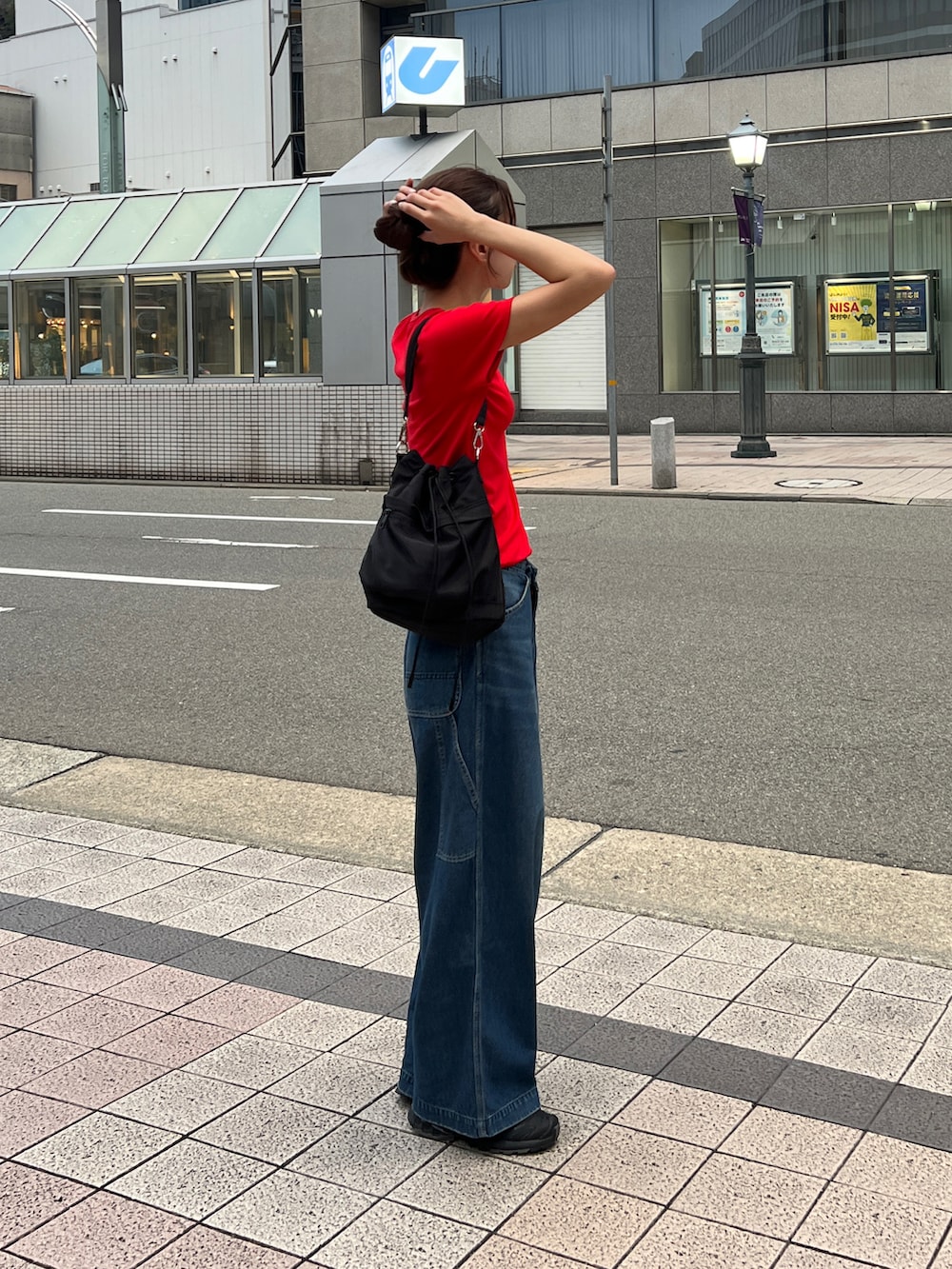 レッド系のTシャツ/カットソー、ブルー系のデニムパンツ、ブラック系のショルダーバッグを着用したレディースの夏コーディネートの2枚目の写真