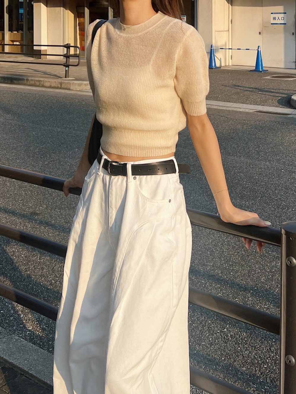 ベージュ系のニット/セーター、ホワイト系のデニムパンツ、ブラック系のスニーカーを着用したレディースの秋コーディネートの3枚目の写真