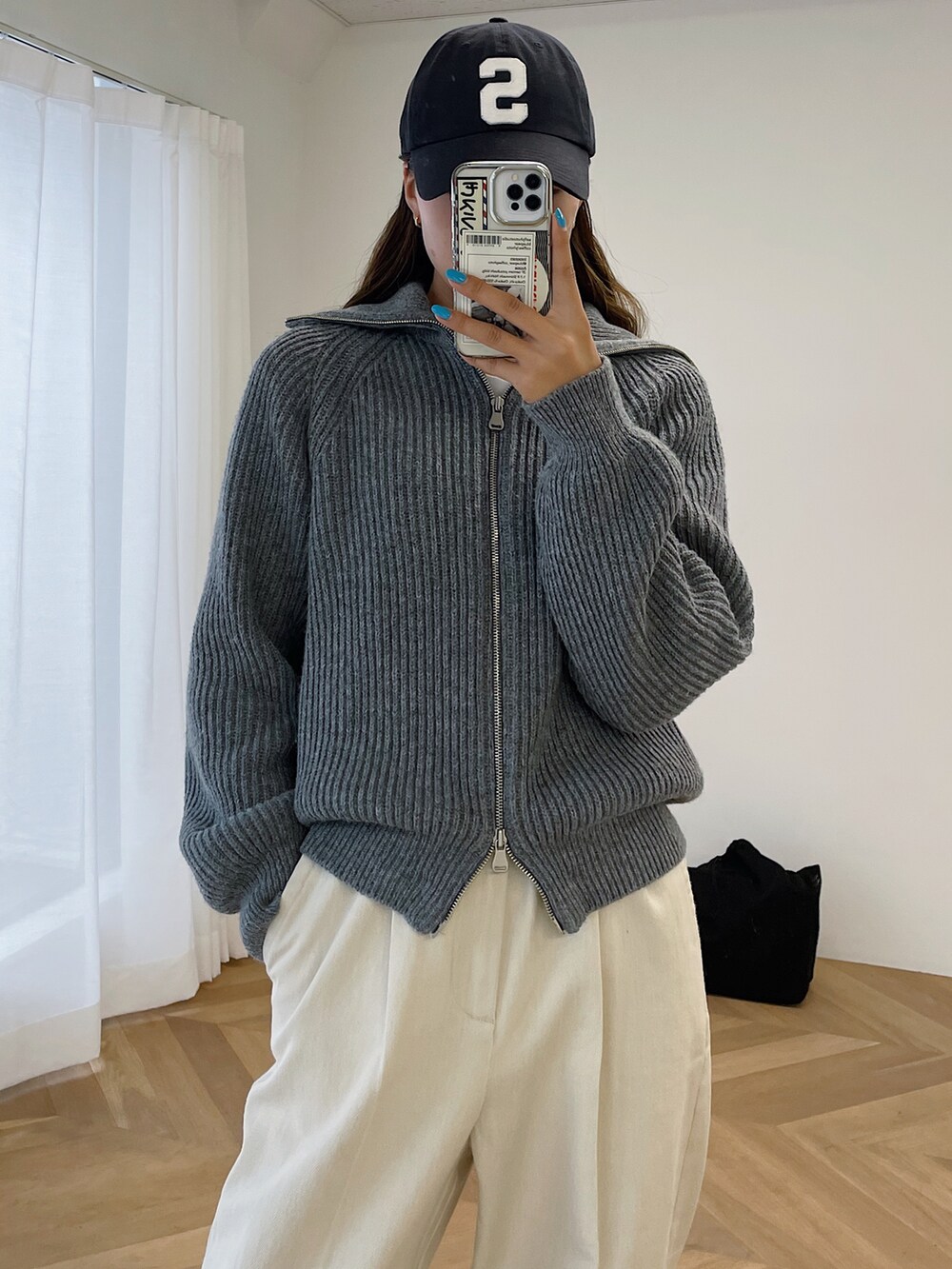 グレー系のカーディガン/ボレロ、ホワイト系のショルダーバッグ、ホワイト系のチノパンツを着用したレディースの秋コーディネートの2枚目の写真