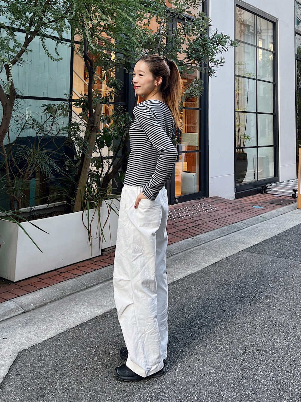 グレー系のTシャツ/カットソー、ホワイト系のチノパンツ、ブラック系のスニーカーを着用したレディースの秋コーディネートの2枚目の写真