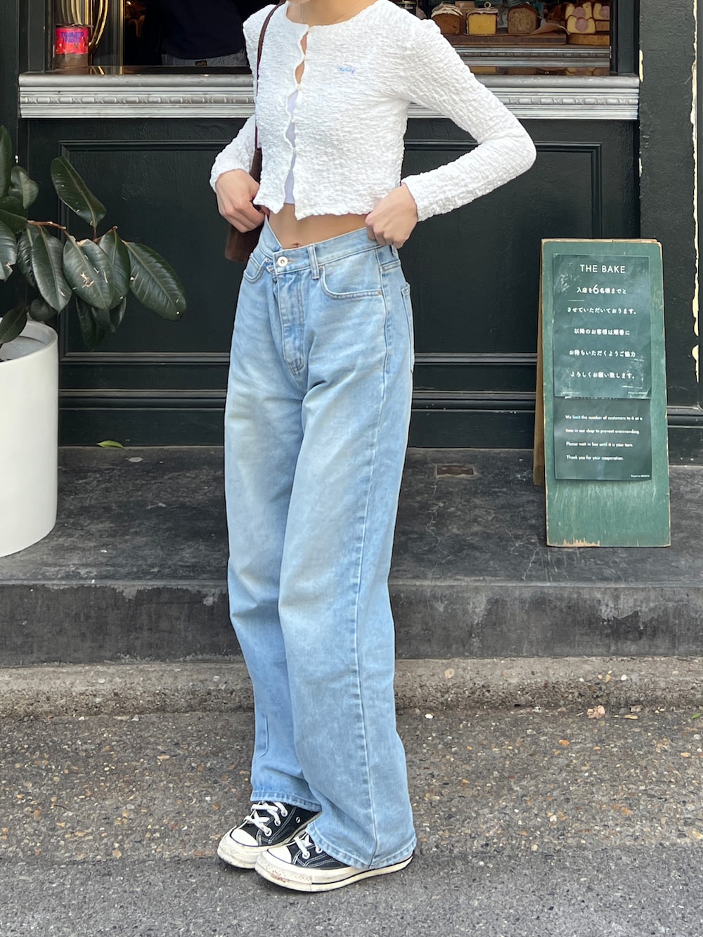 ホワイト系のカーディガン/ボレロ、ブルー系のデニムパンツ、ブラウン系のハンドバッグを着用したレディースの春コーディネートの3枚目の写真