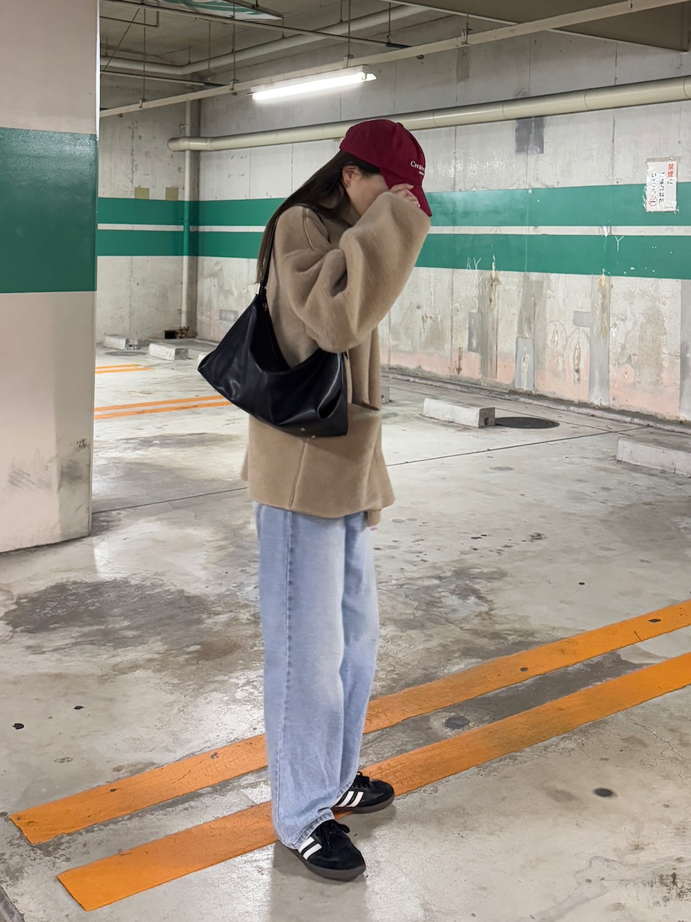 ベージュ系のブルゾン、ブルー系のデニムパンツ、ブラック系のスニーカーを着用したレディースの冬コーディネートの2枚目の写真