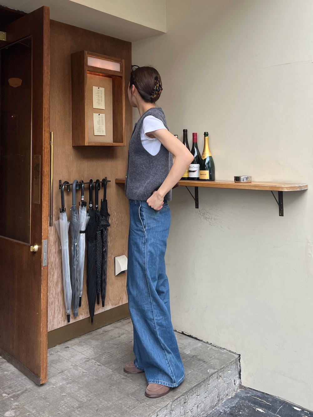 グレー系のベスト、ブルー系のチノパンツ、ブラウン系のモカシン/デッキシューズを着用したレディースの春コーディネートの2枚目の写真