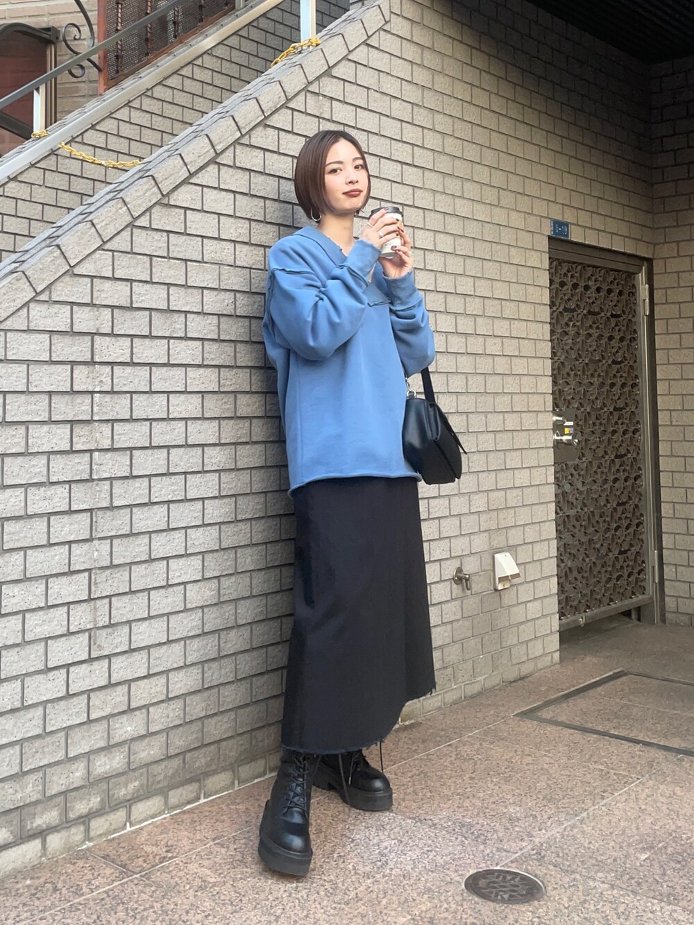 ブルー系のTシャツ/カットソー、ブラック系のハンドバッグ、ブラック系のスカートを着用したレディースの秋コーディネートの2枚目の写真