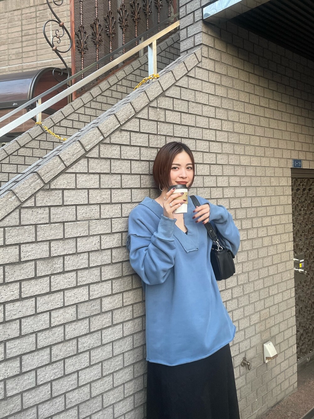 ブルー系のTシャツ/カットソー、ブラック系のハンドバッグ、ブラック系のスカートを着用したレディースの秋コーディネートの4枚目の写真