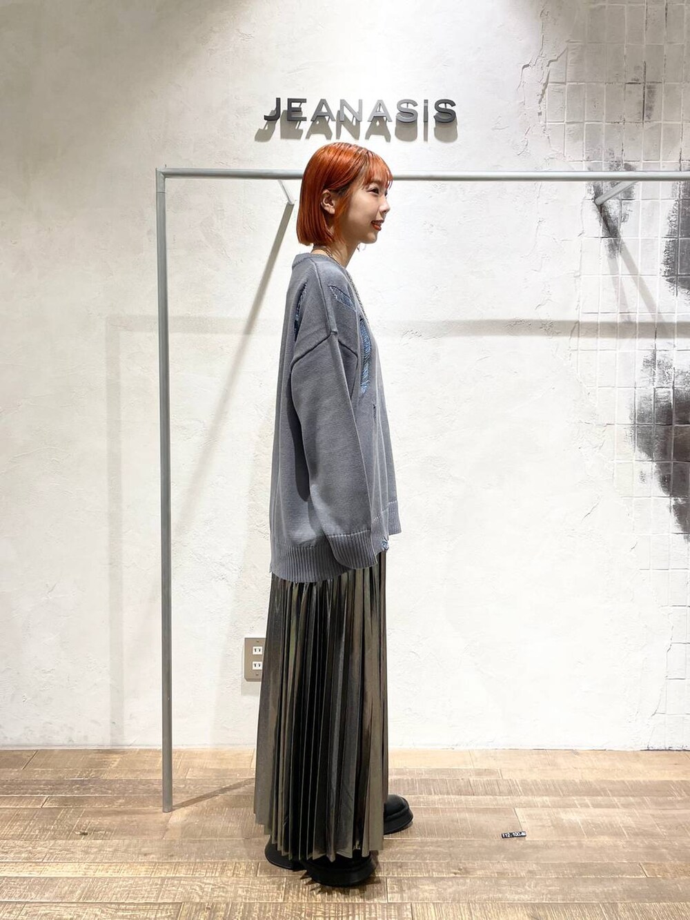 ブラック系のブーツ、シルバー系のスカート、グレー系のニット/セーターを着用したレディースの秋コーディネートの2枚目の写真