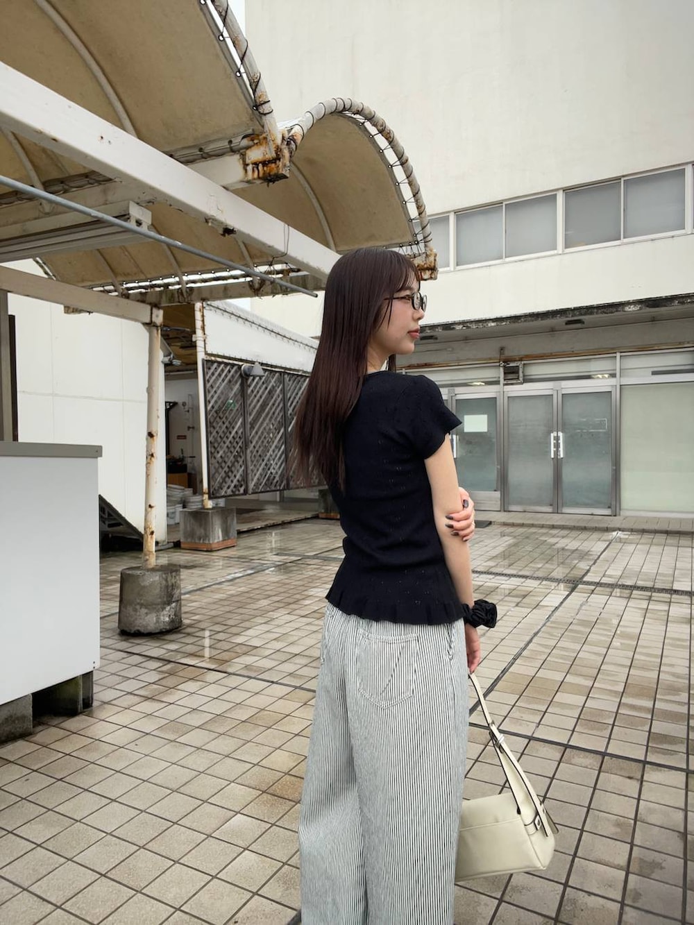 ブラック系のパンプス、ホワイト系のショルダーバッグ、ホワイト系のデニムパンツを着用したレディースの夏コーディネートの3枚目の写真