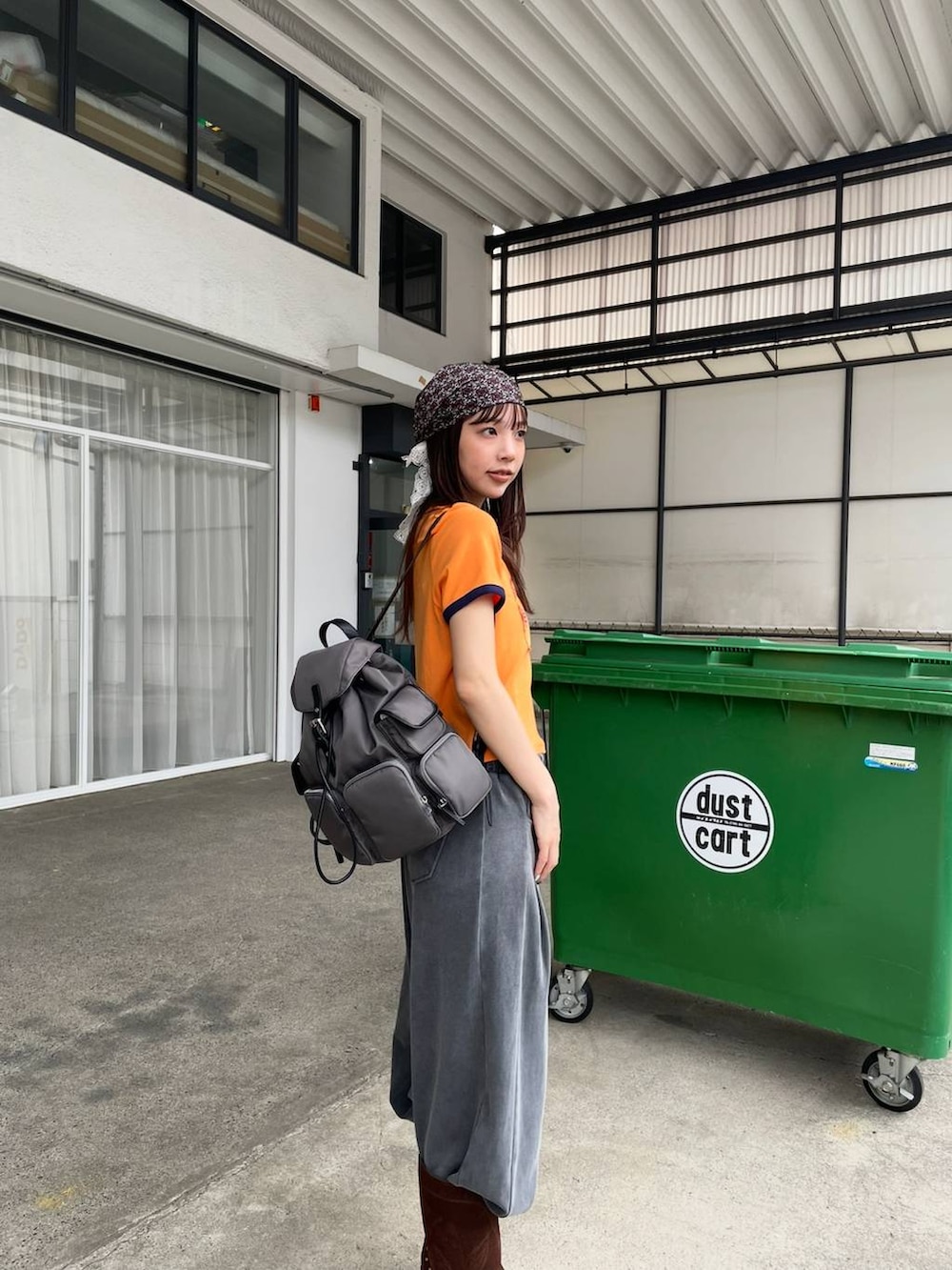 オレンジ系のTシャツ/カットソー、グレー系のバックパック/リュック、ブラウン系のブーツを着用したレディースの夏コーディネートの4枚目の写真