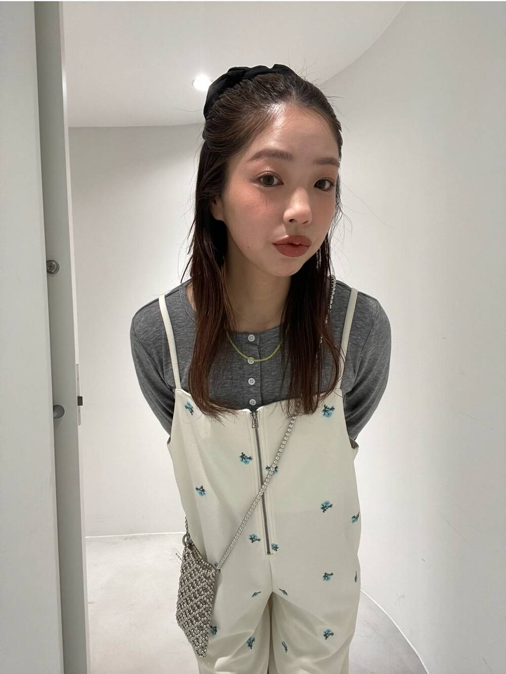 シルバー系のパンプス、ホワイト系のサロペット/オーバーオール、グレー系のTシャツ/カットソーを着用したレディースの冬コーディネートの2枚目の写真