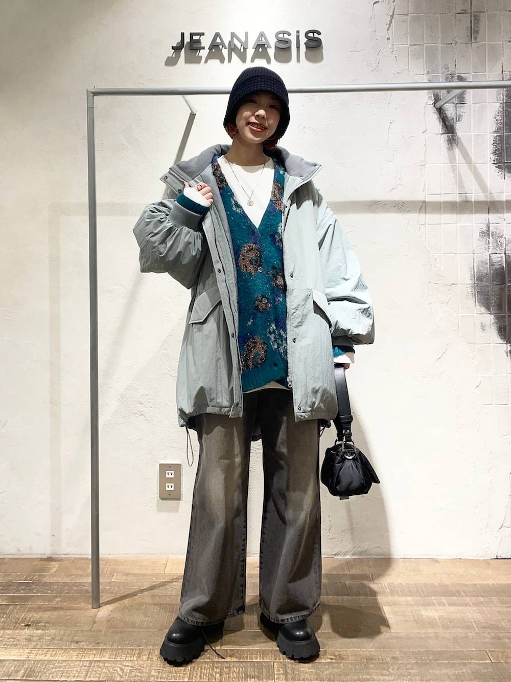 ブラック系のデニムパンツ、ブラック系のショルダーバッグ、ブラック系のブーツを着用したレディースの冬コーディネートの2枚目の写真