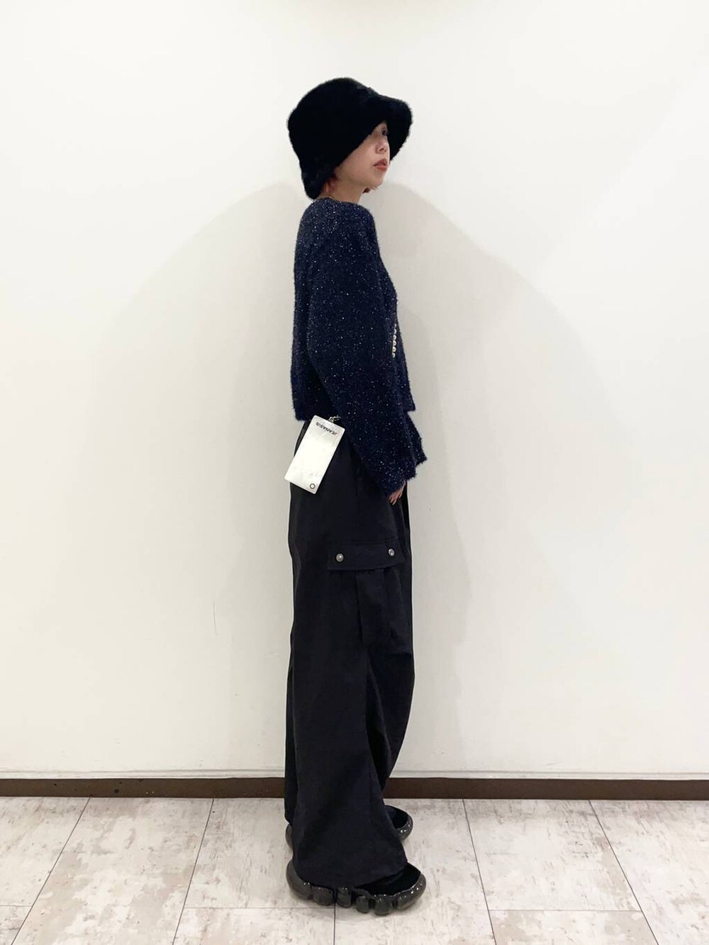 ブルー系のニット/セーター、ブラック系のカーゴパンツ、シルバー系のスマホグッズを着用したレディースの冬コーディネートの2枚目の写真