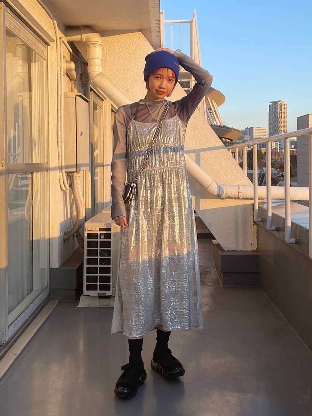 ブラック系のショルダーバッグ、ブルー系のTシャツ/カットソー、シルバー系のワンピースを着用したレディースの冬コーディネートの3枚目の写真