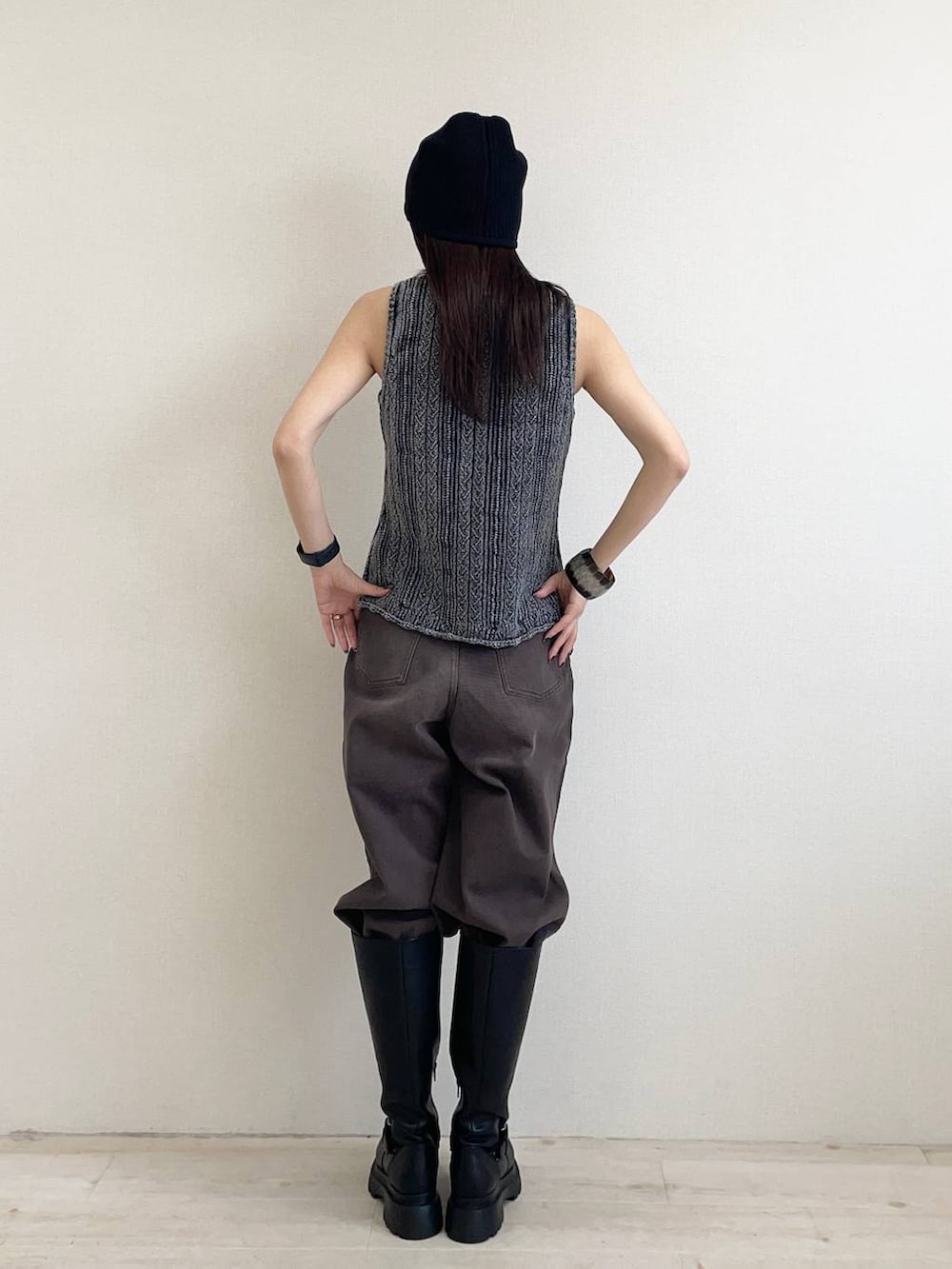 ブラウン系のデニムパンツ、ブラック系のベスト、ブラック系のブーツを着用したレディースの夏コーディネートの2枚目の写真