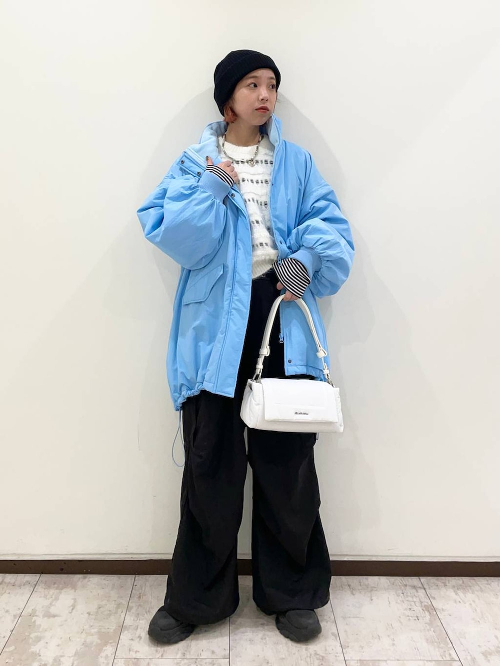 ブラック系のブーツ、ホワイト系のショルダーバッグ、ブラック系のカーゴパンツを着用したレディースの冬コーディネートの2枚目の写真