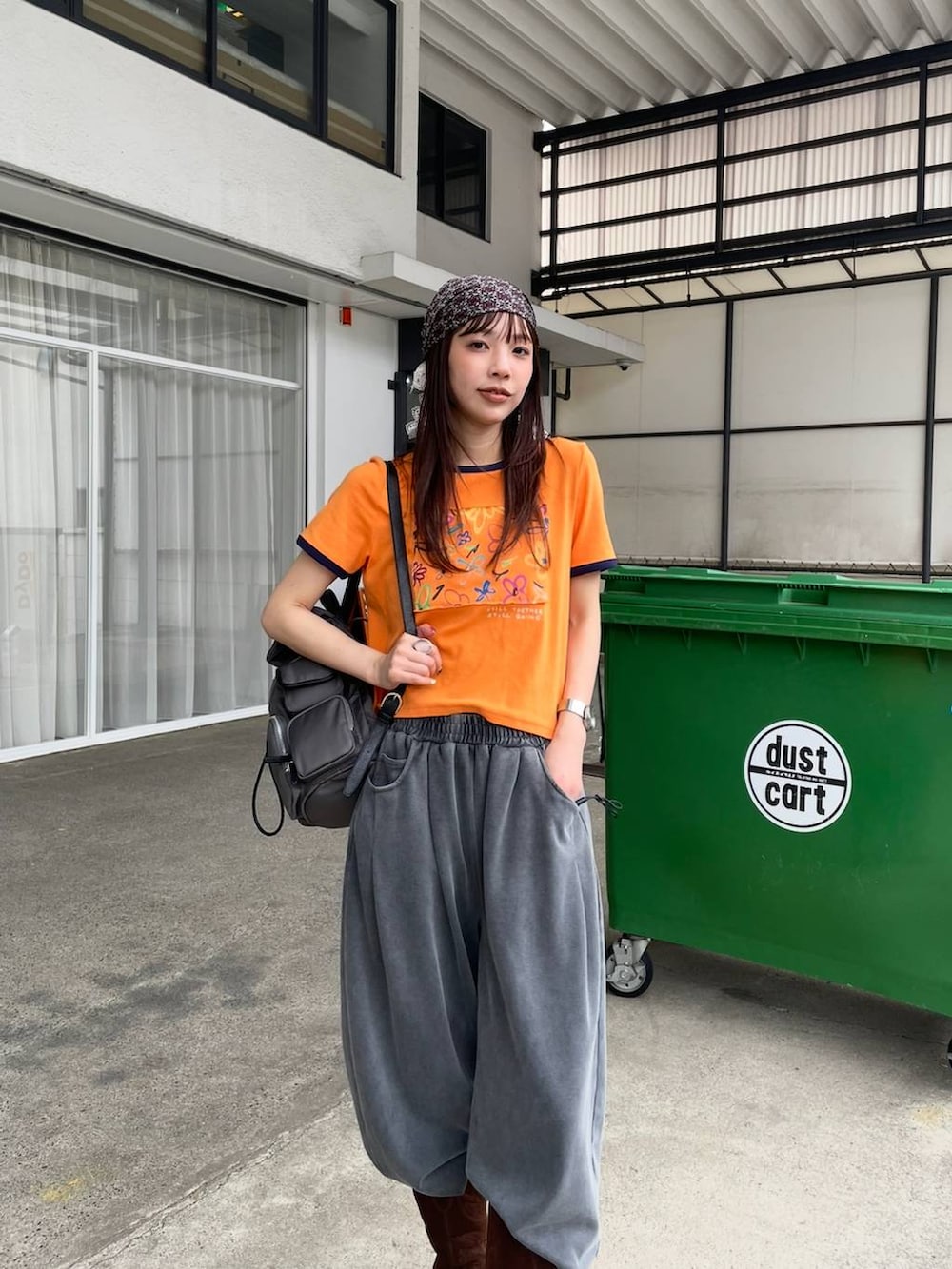 オレンジ系のTシャツ/カットソー、グレー系のバックパック/リュック、ブラウン系のブーツを着用したレディースの夏コーディネートの2枚目の写真