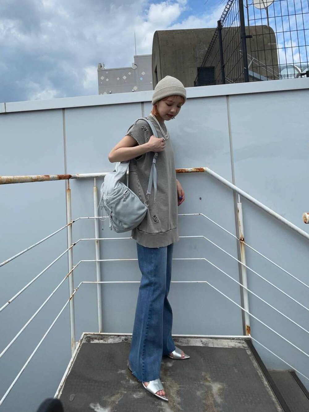 シルバー系のサンダル、グレー系のショルダーバッグ、ブルー系のデニムパンツを着用したレディースの夏コーディネートの4枚目の写真