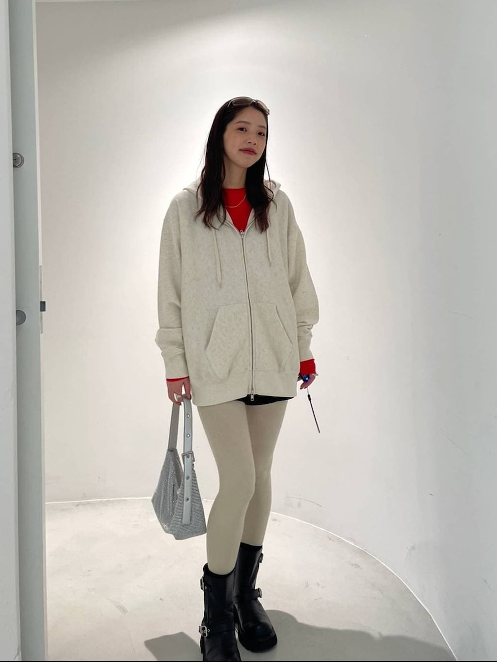 ブラック系のブーツ、ベージュ系のパーカー、シルバー系のハンドバッグを着用したレディースの冬コーディネートの3枚目の写真