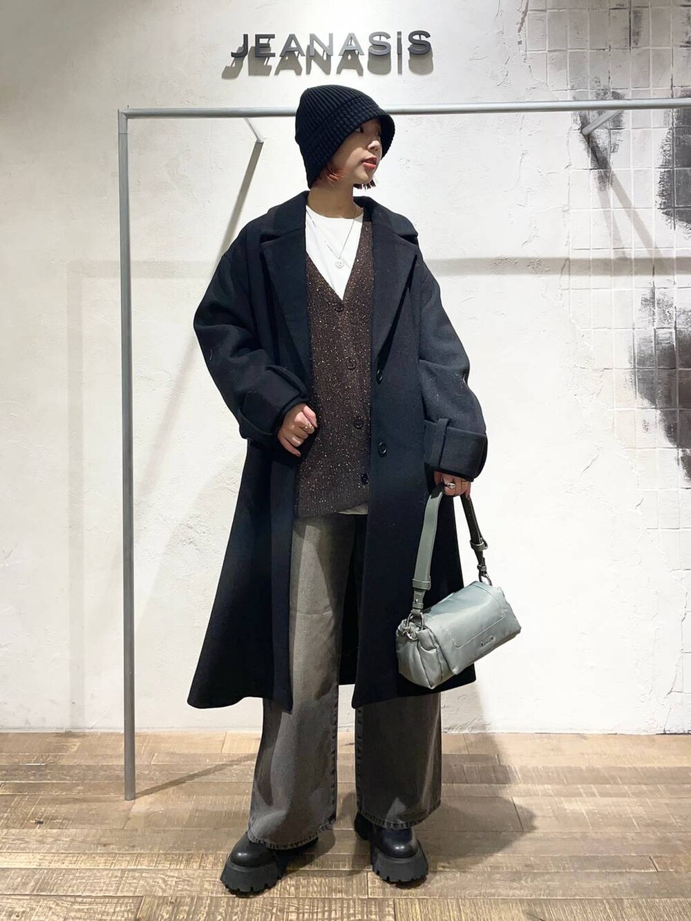 ブラック系のデニムパンツ、グリーン系のショルダーバッグ、ブラック系のブーツを着用したレディースの冬コーディネートの3枚目の写真