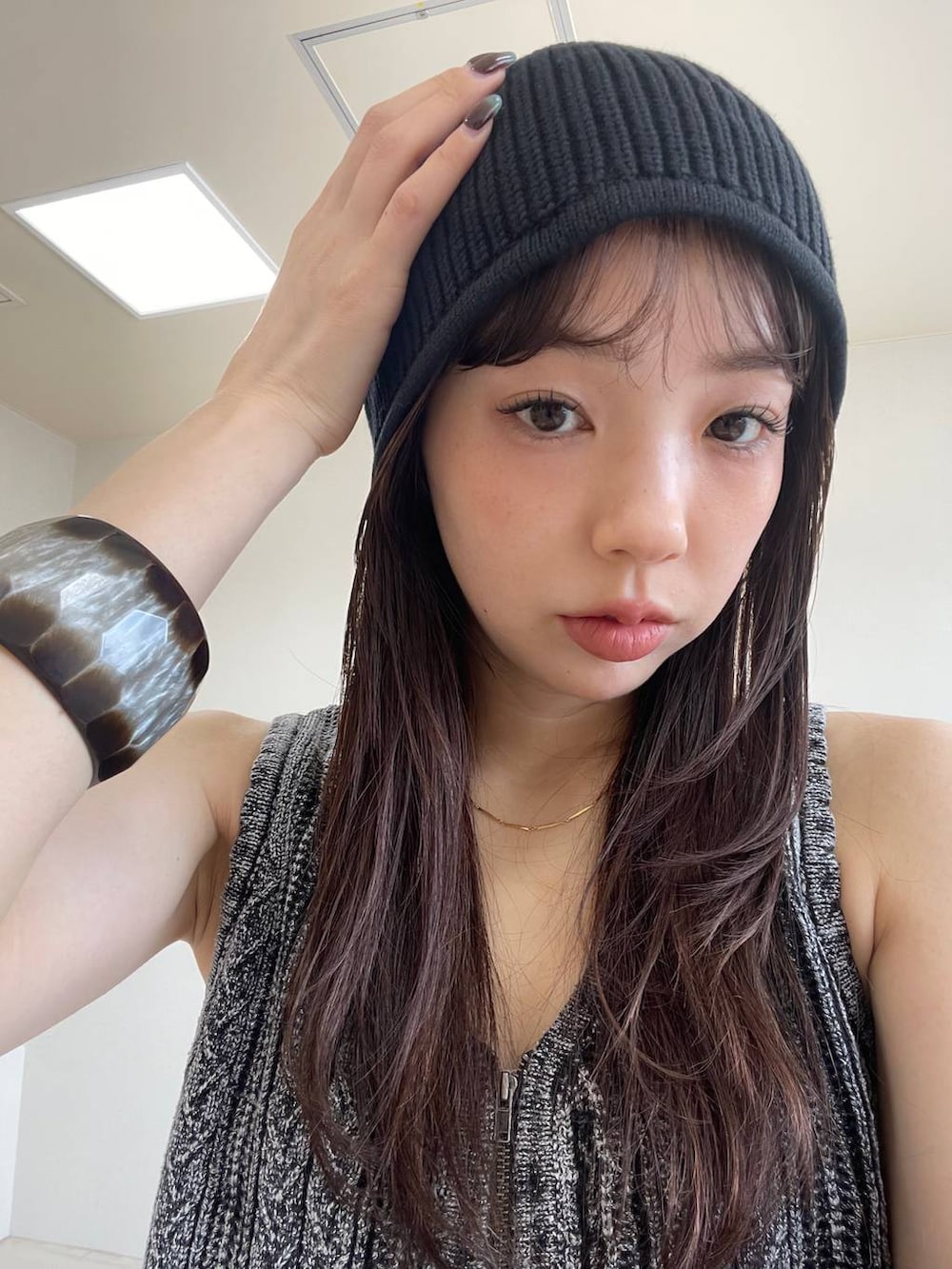 ブラウン系のデニムパンツ、ブラック系のベスト、ブラック系のブーツを着用したレディースの夏コーディネートの3枚目の写真
