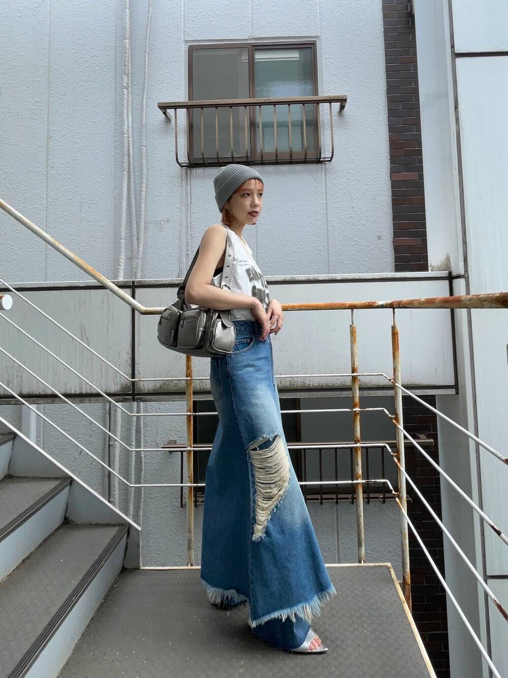 シルバー系のサンダル、ブルー系のスカート、シルバー系のショルダーバッグを着用したレディースの夏コーディネートの2枚目の写真