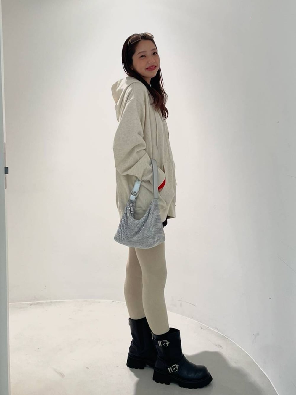 ブラック系のブーツ、ベージュ系のパーカー、シルバー系のハンドバッグを着用したレディースの冬コーディネートの2枚目の写真