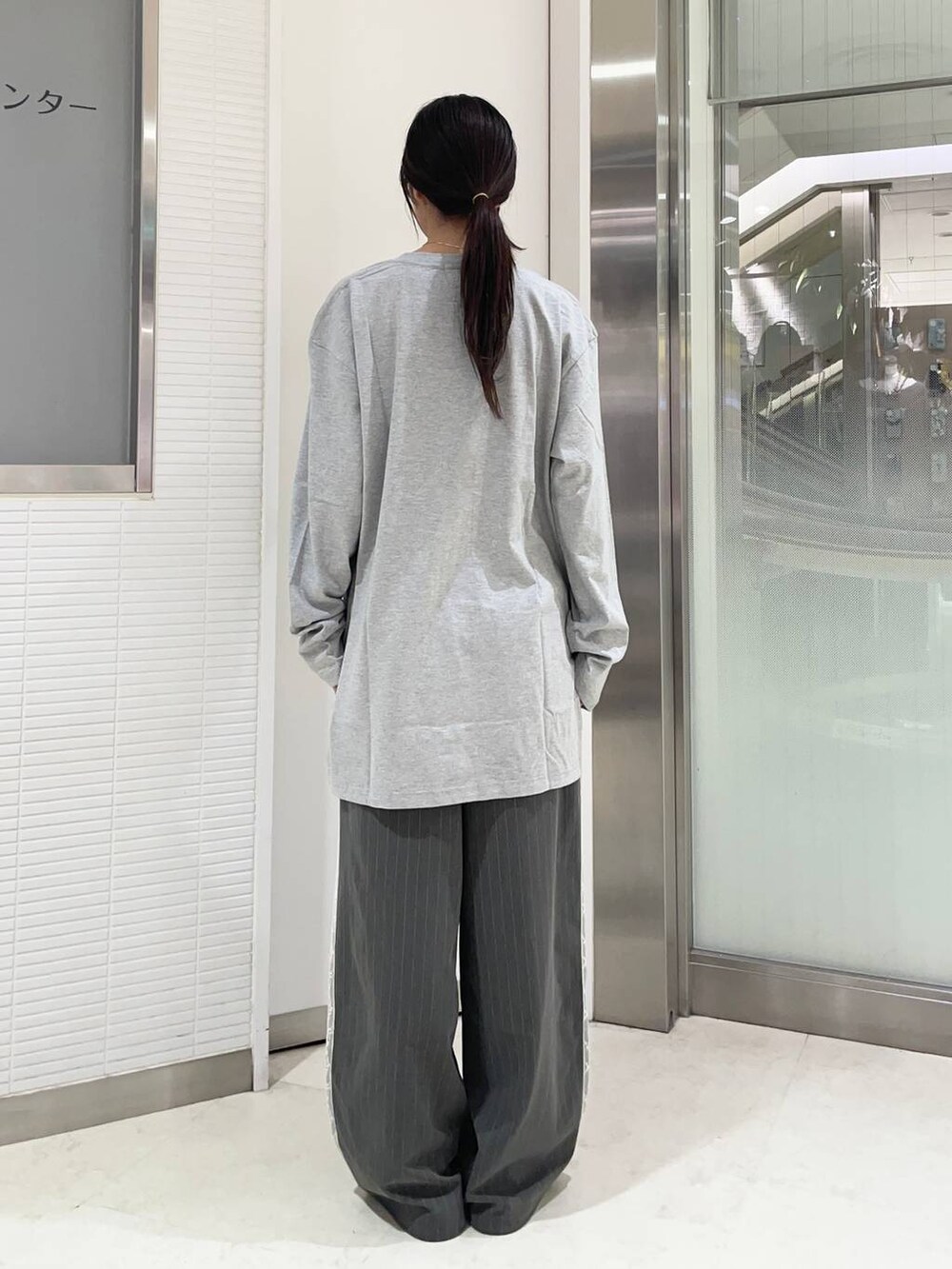 ブラック系のローファー、グレー系のスラックス、グレー系のTシャツ/カットソーを着用したレディースの夏コーディネートの2枚目の写真
