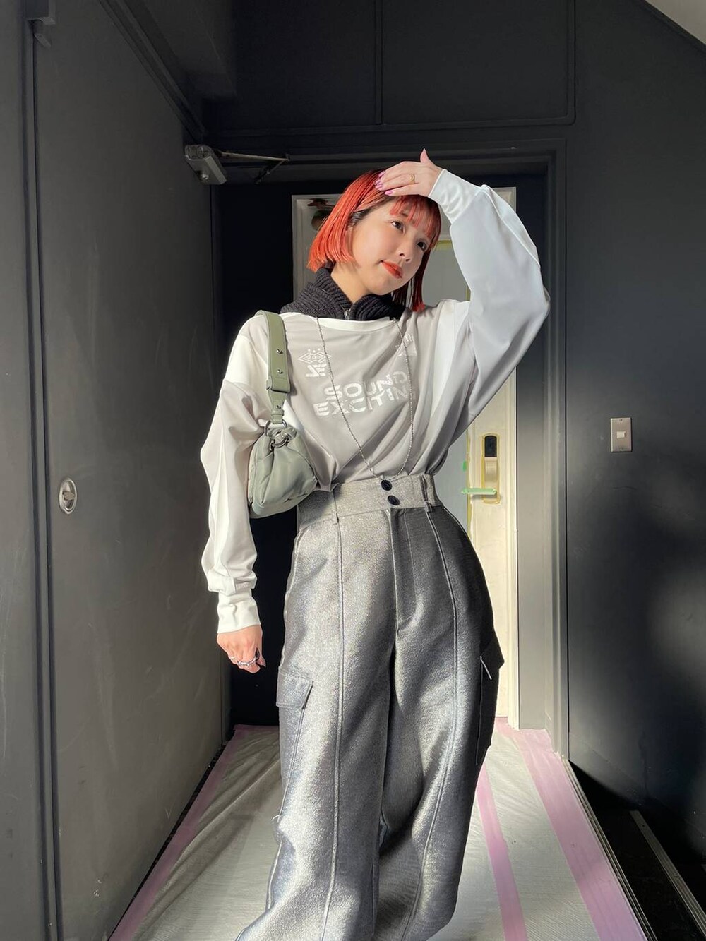 グレー系のTシャツ/カットソー、グリーン系のショルダーバッグ、ブラック系のブーツを着用したレディースの冬コーディネートの3枚目の写真