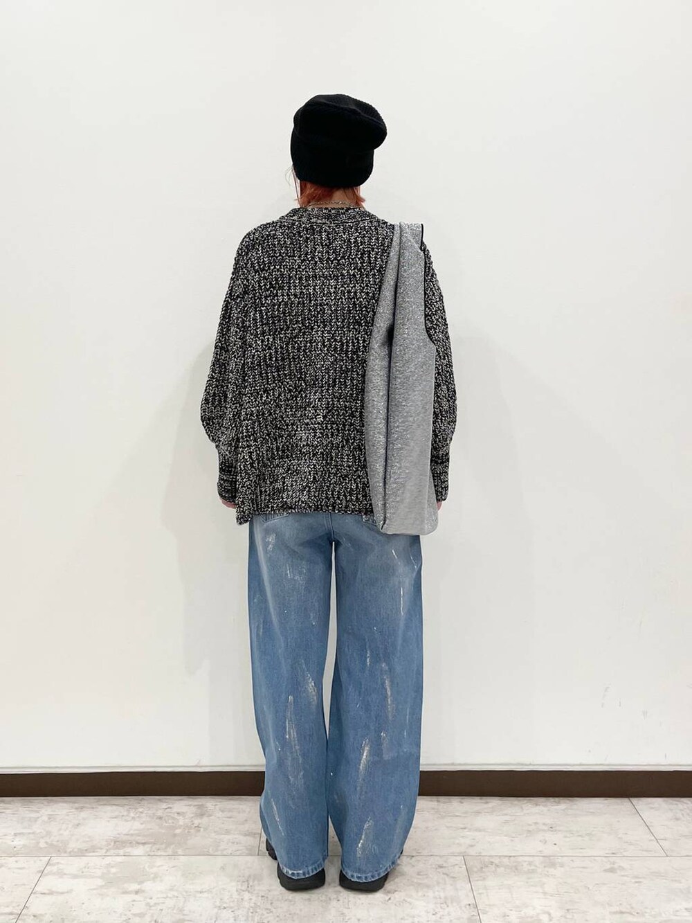 シルバー系のトートバッグ、ブラック系のブーツ、ブルー系のデニムパンツを着用したレディースの秋コーディネートの3枚目の写真