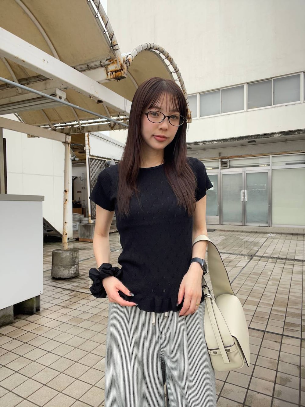 ブラック系のパンプス、ホワイト系のショルダーバッグ、ホワイト系のデニムパンツを着用したレディースの夏コーディネートの2枚目の写真