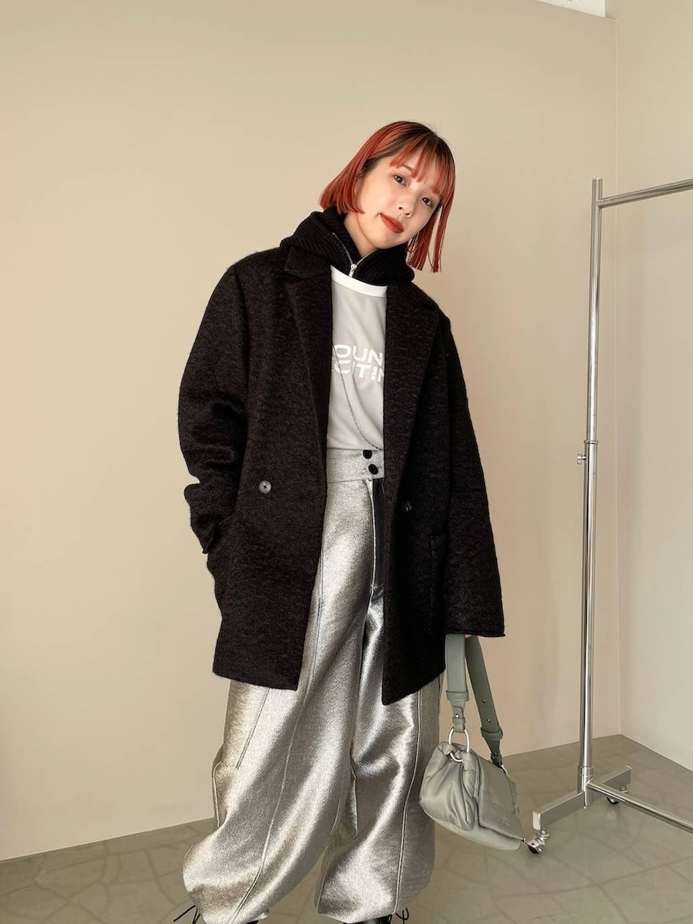 ブラック系のテーラードジャケット、グリーン系のショルダーバッグ、ブラック系のブーツを着用したレディースの冬コーディネートの2枚目の写真