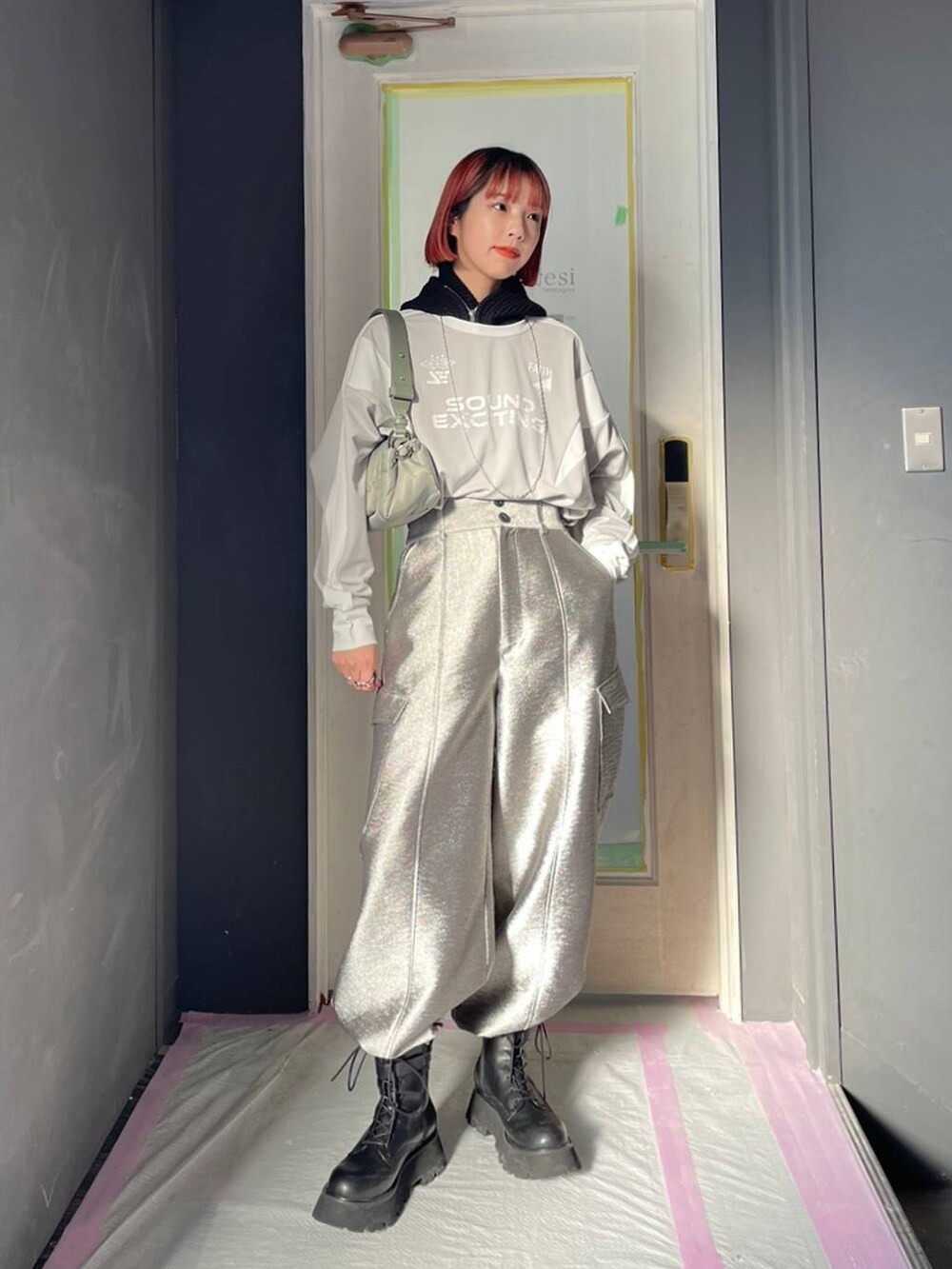 グレー系のTシャツ/カットソー、グリーン系のショルダーバッグ、ブラック系のブーツを着用したレディースの冬コーディネートの2枚目の写真