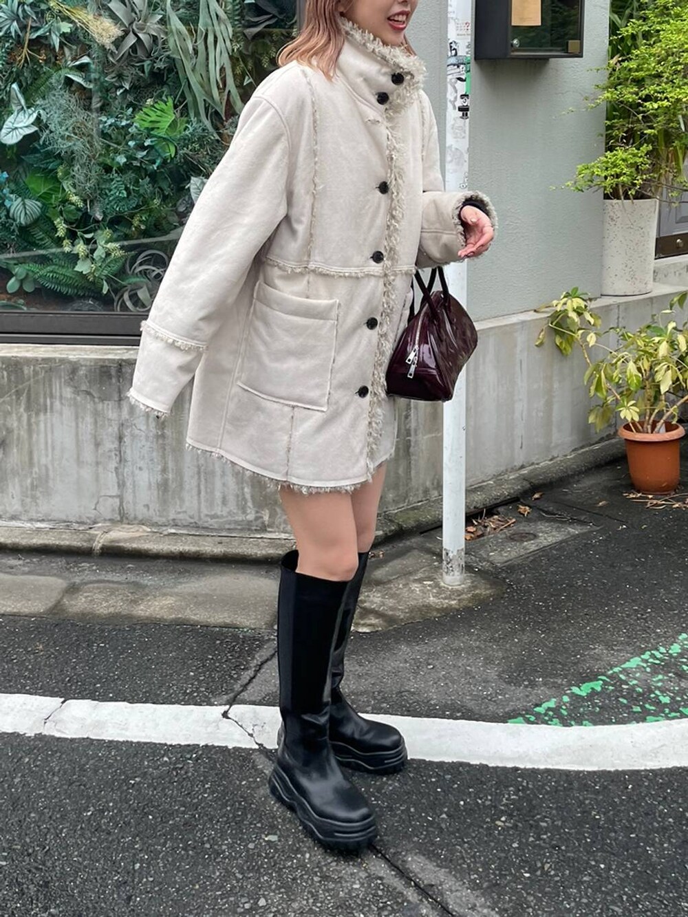 ブラック系のブーツ、レッド系のボストンバッグ、ホワイト系のブルゾンを着用したレディースの冬コーディネートの2枚目の写真