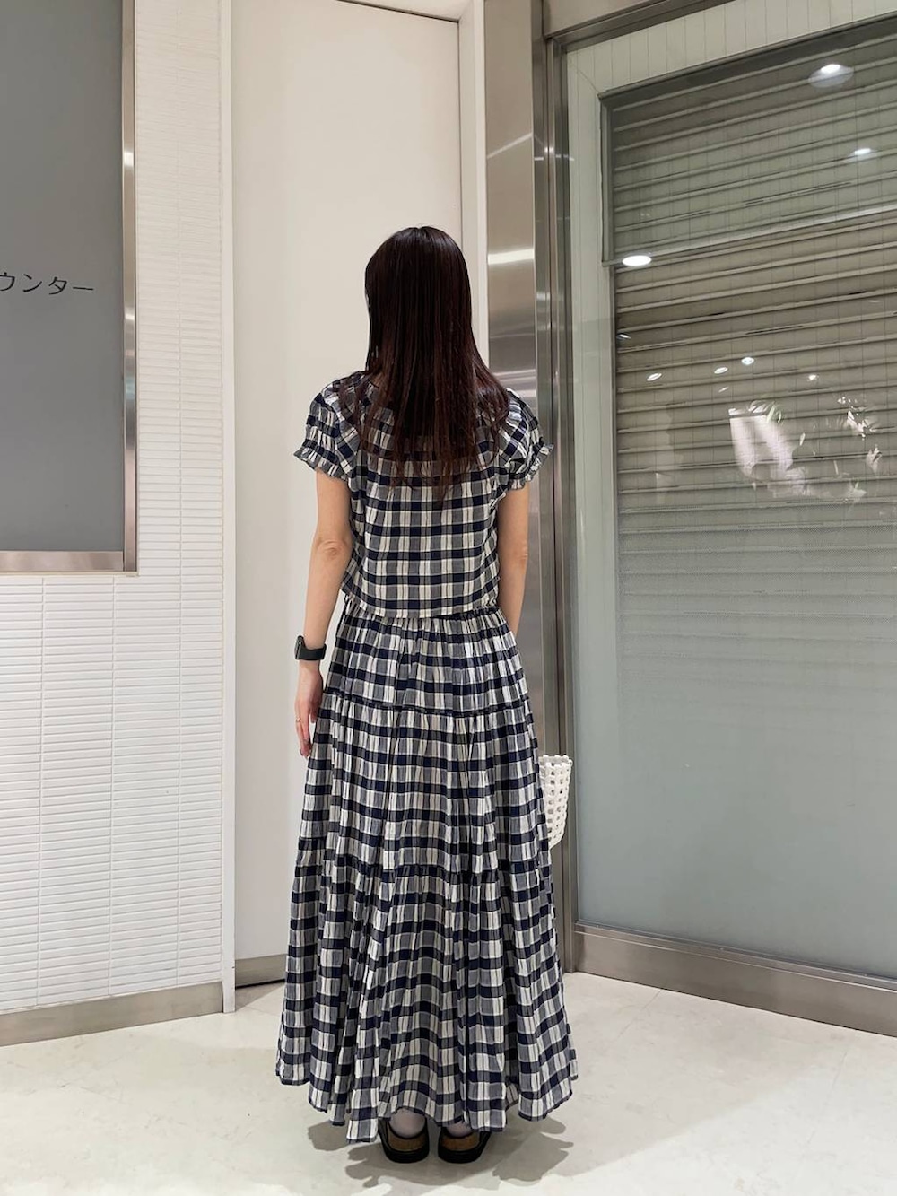 ブラック系のローファー、ホワイト系のハンドバッグ、ブルー系のシャツ/ブラウスを着用したレディースの夏コーディネートの2枚目の写真