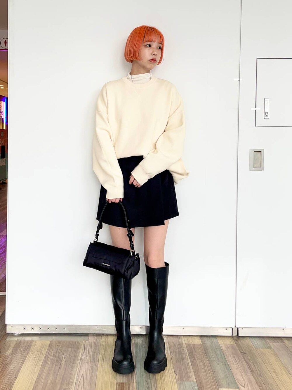 ホワイト系のニット/セーター、ホワイト系のTシャツ/カットソー、ブラック系のブーツを着用したレディースの冬コーディネートの2枚目の写真