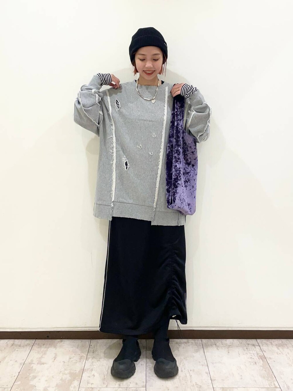 パープル系のトートバッグ、ブラック系のブーツ、グレー系のスウェットを着用したレディースの冬コーディネートの2枚目の写真